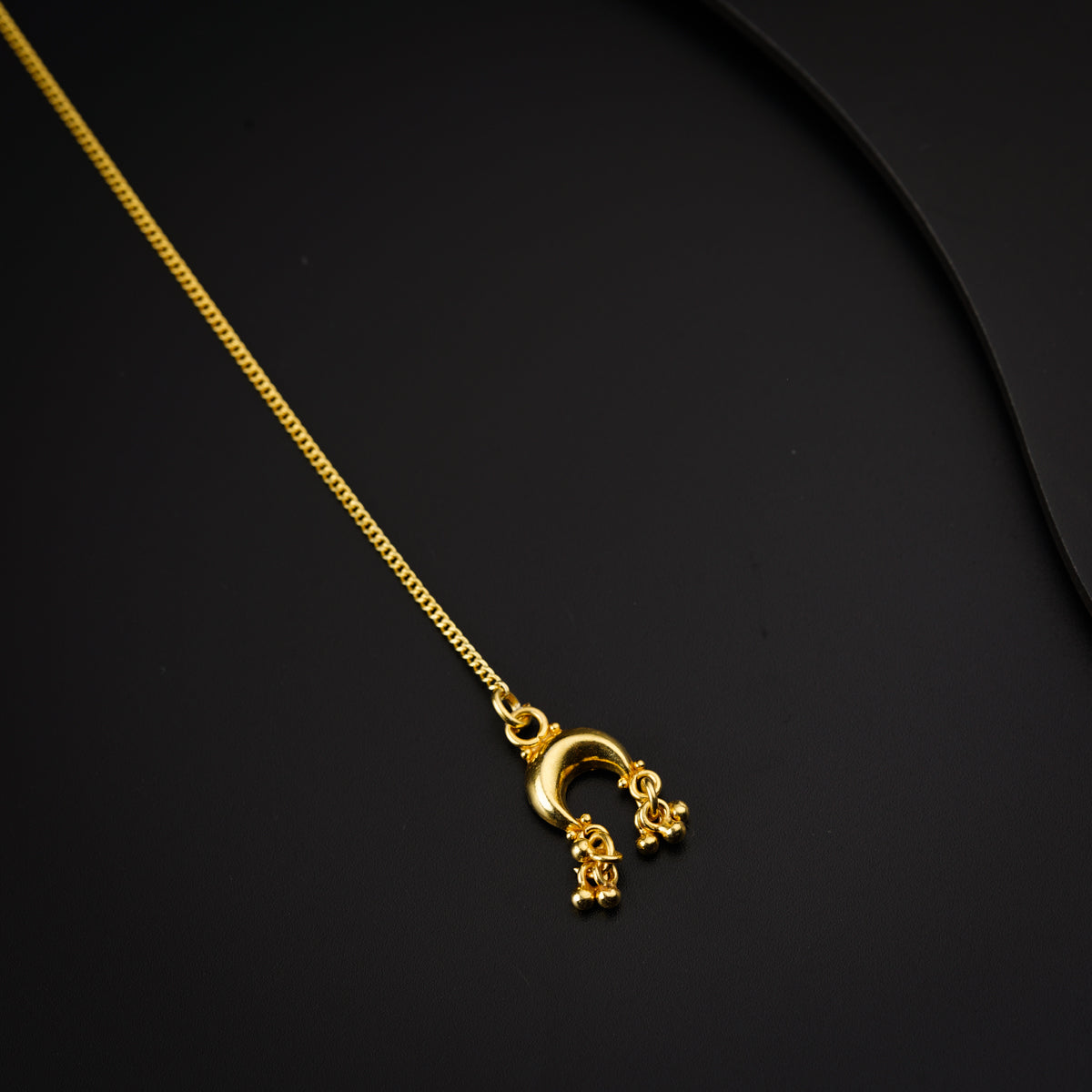 a gold necklace on a black surface