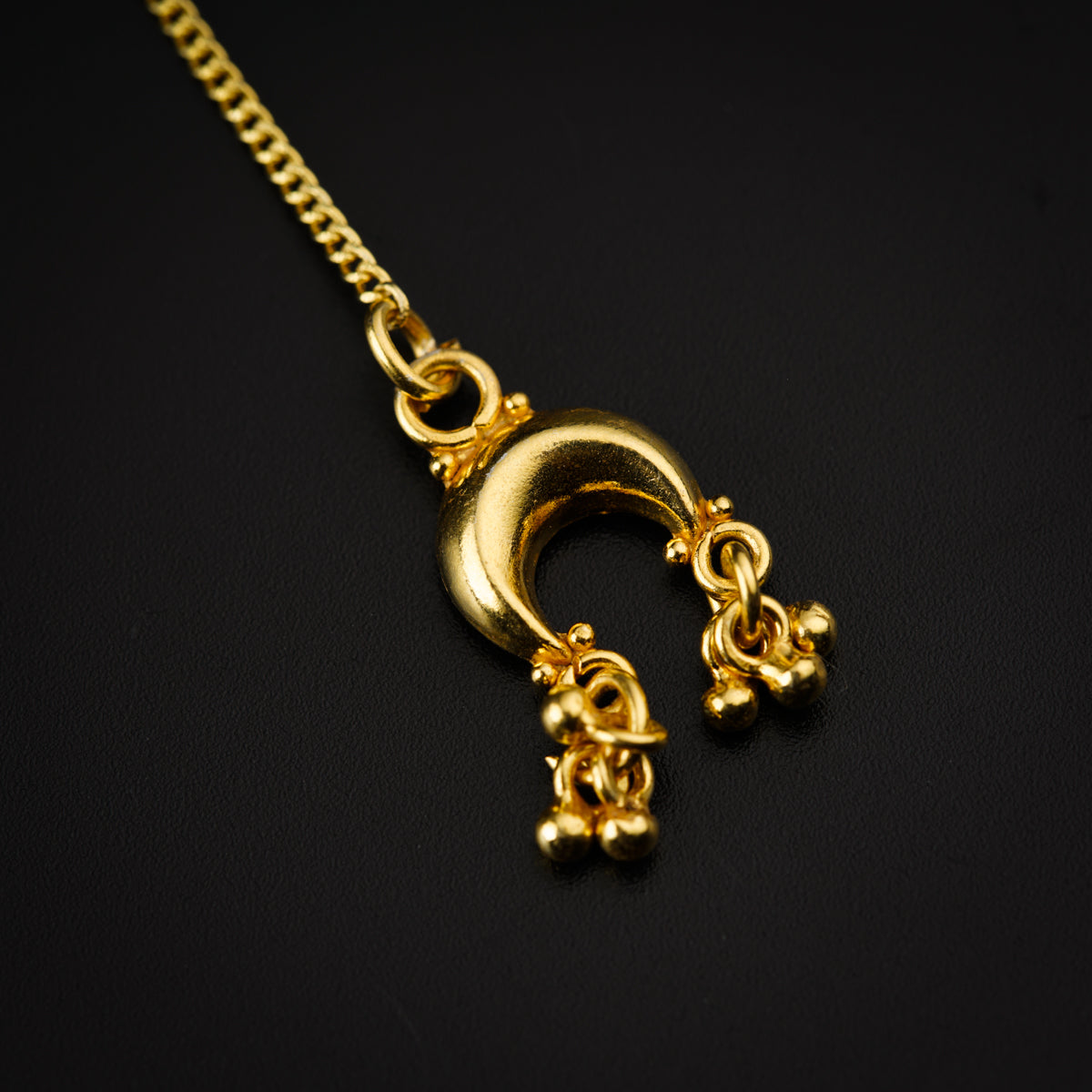 a gold necklace on a black background