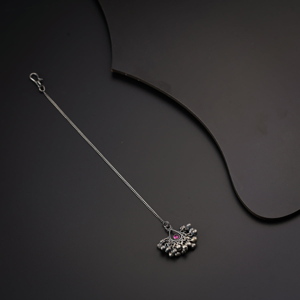 a silver necklace on a black surface