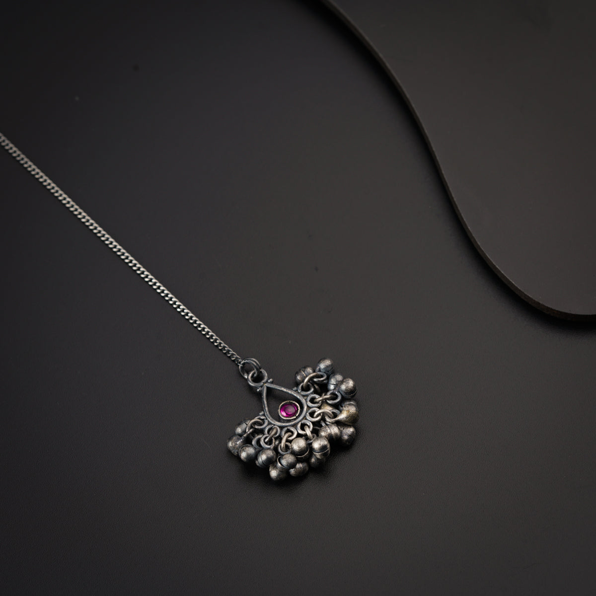 a silver necklace with a pink stone in the center