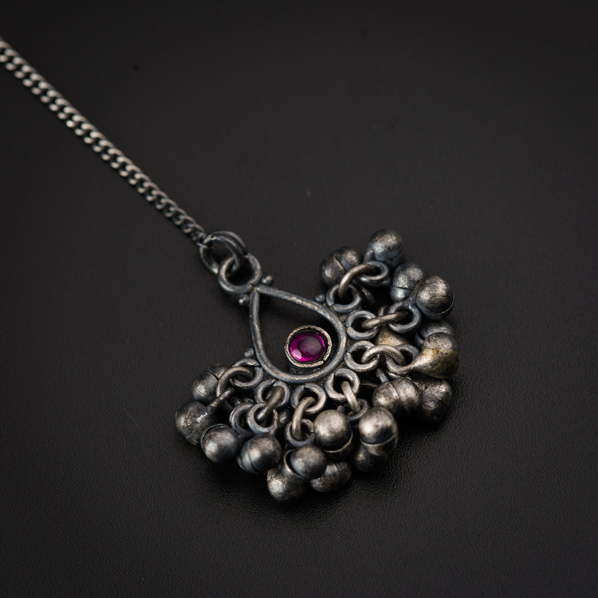 a silver necklace with a red stone in the center