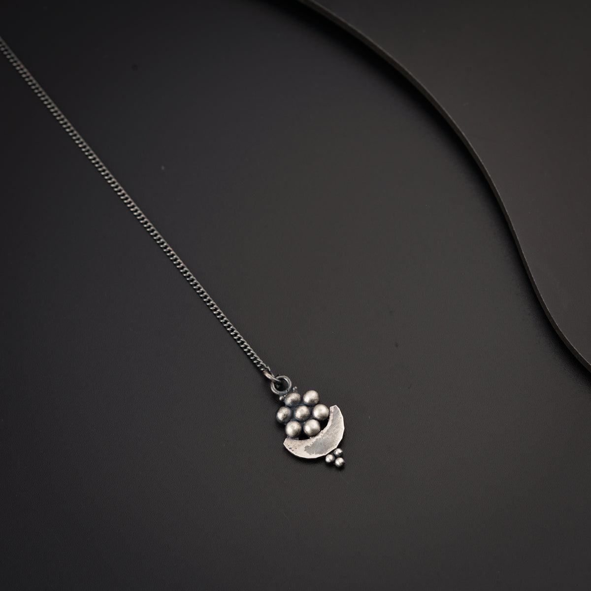 a silver necklace on a black surface