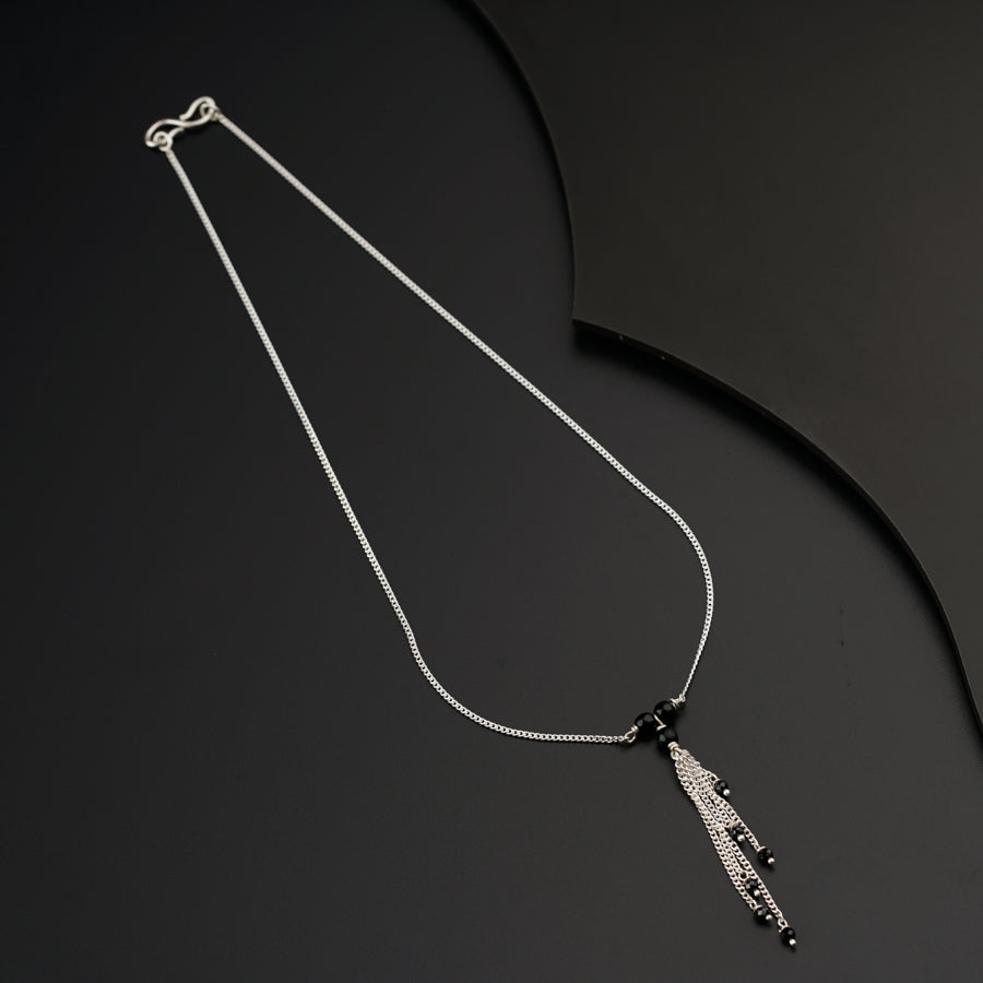 a necklace with a feather on a black background