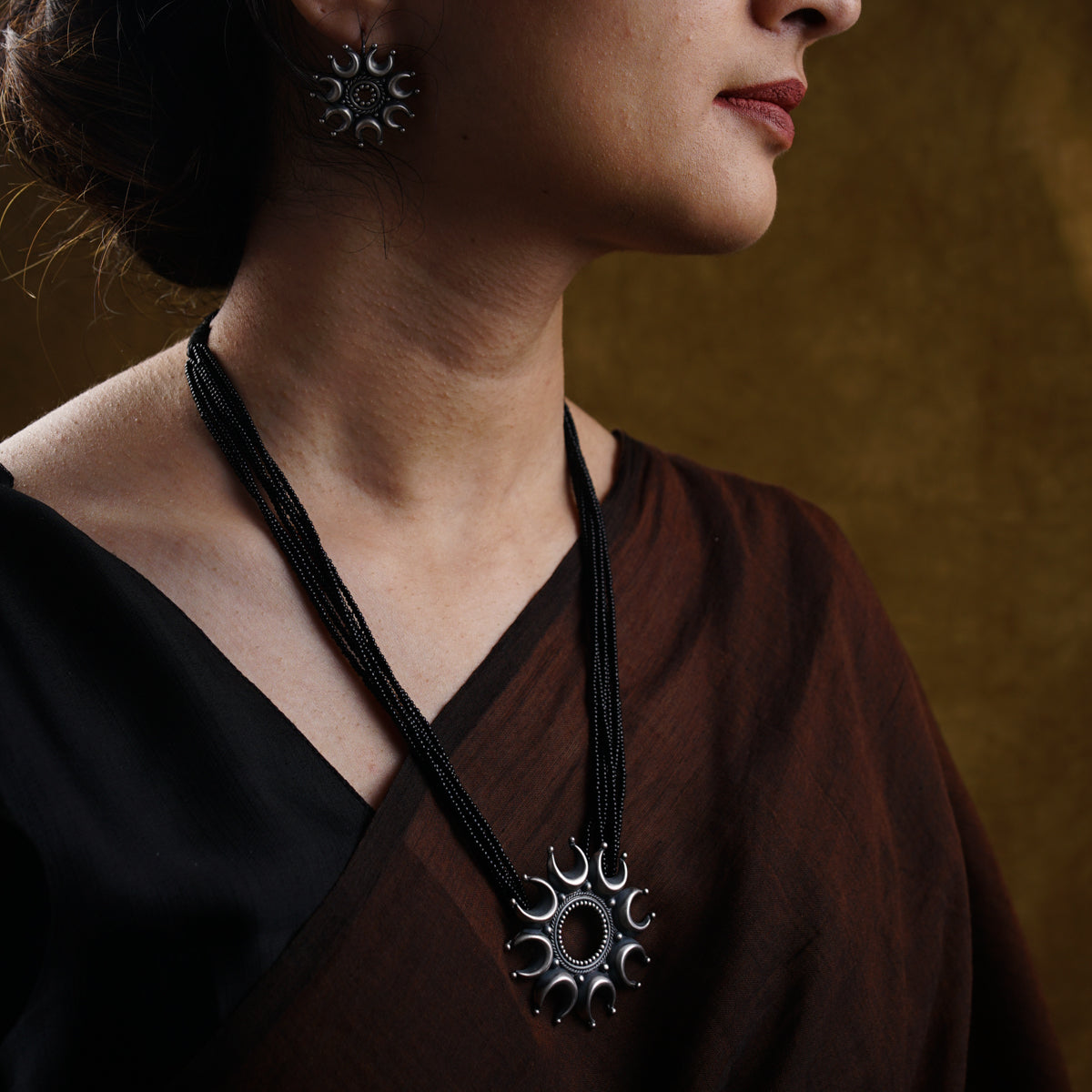 a woman wearing a necklace and earrings
