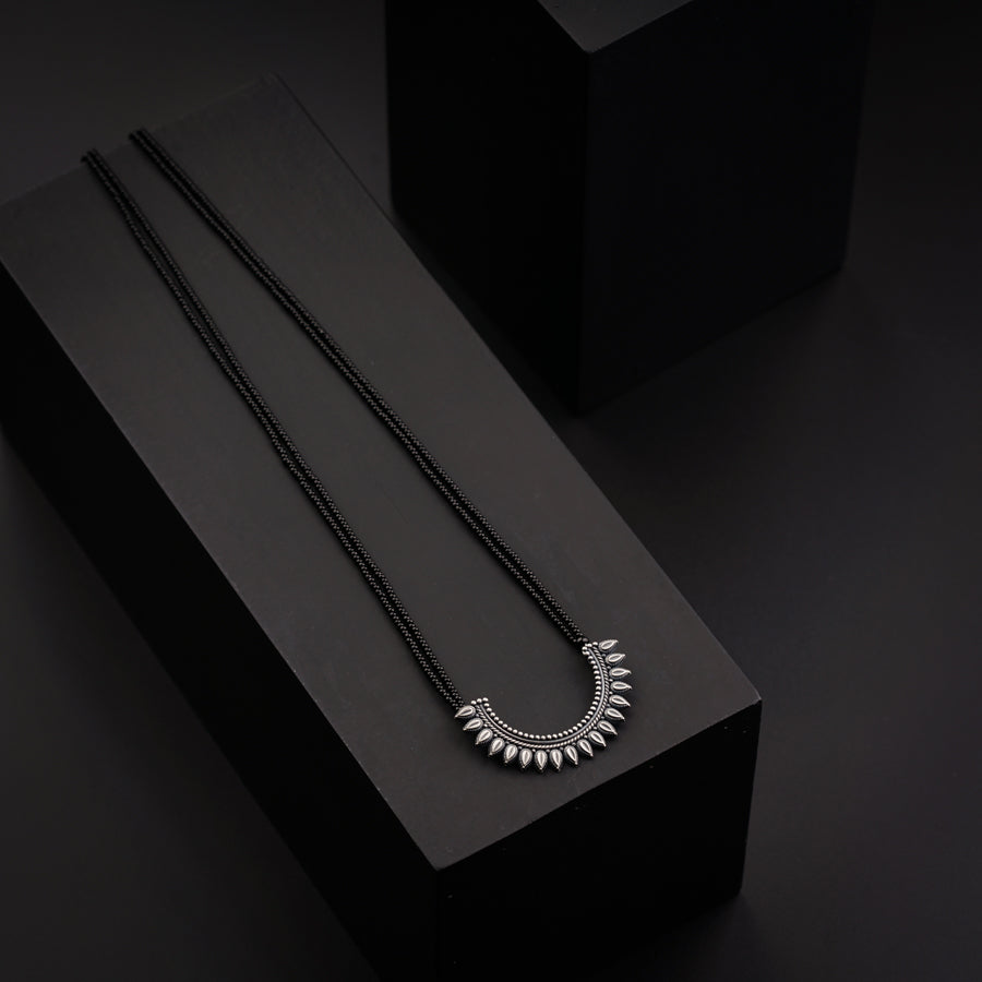 two necklaces sitting on top of a black box