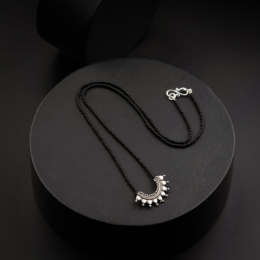 a black necklace with a silver pendant on it