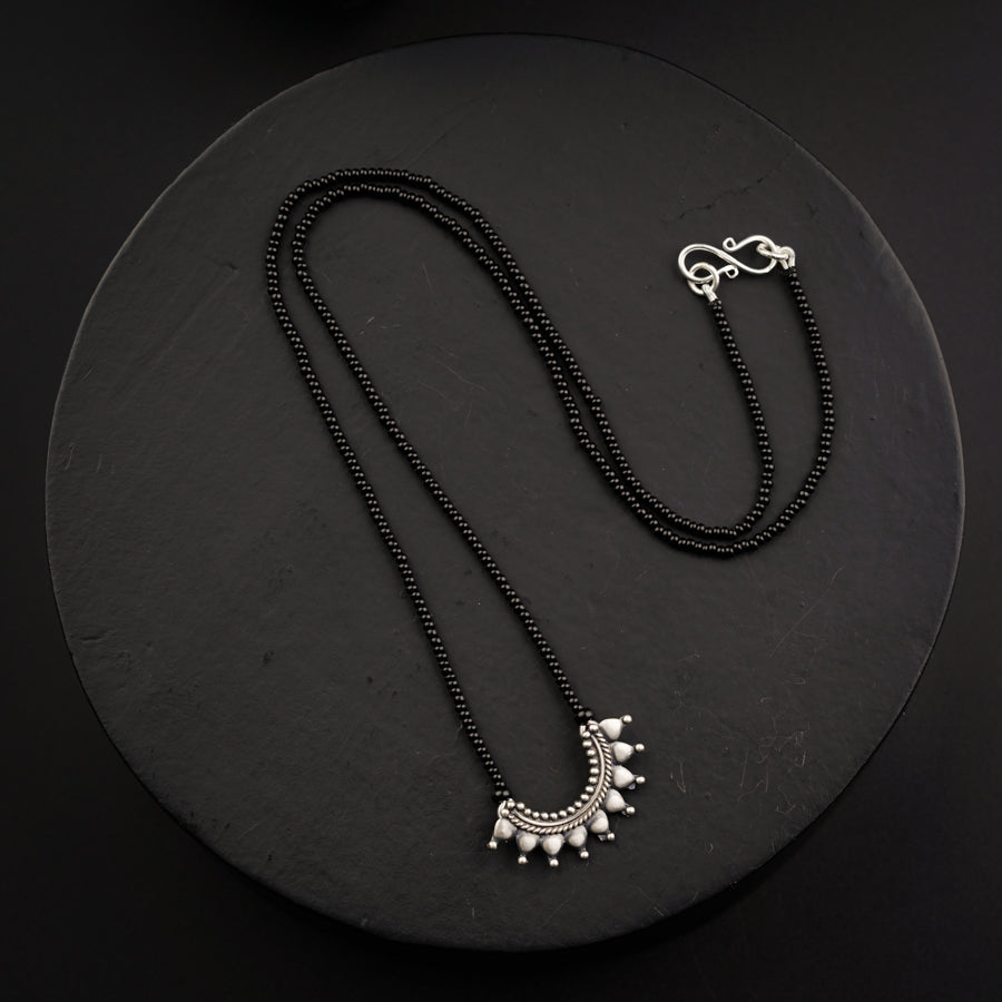 a necklace and earring on a black plate