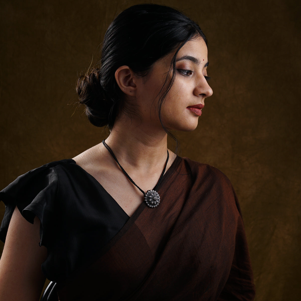 a woman wearing a brown dress and a necklace