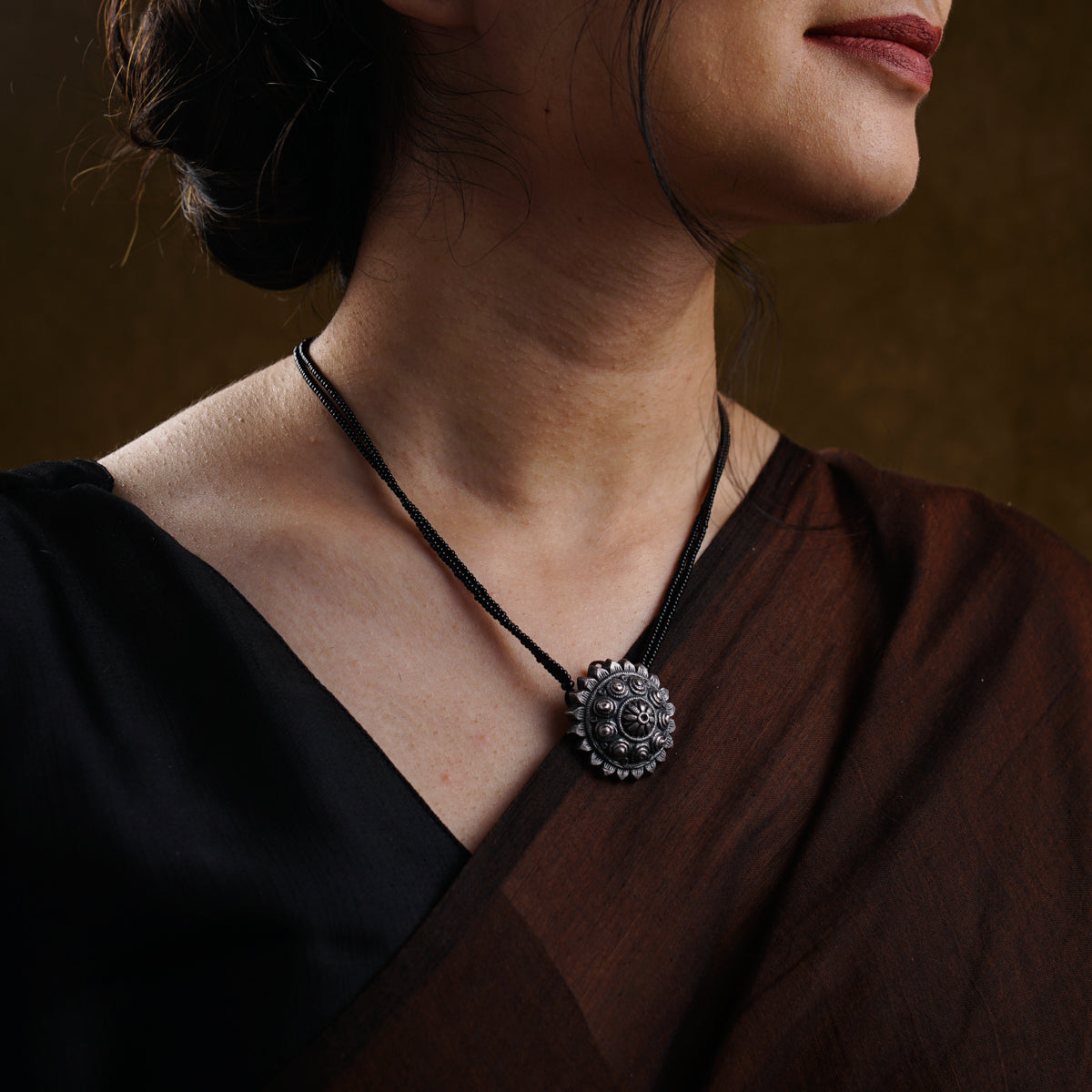 a woman wearing a necklace with a flower on it