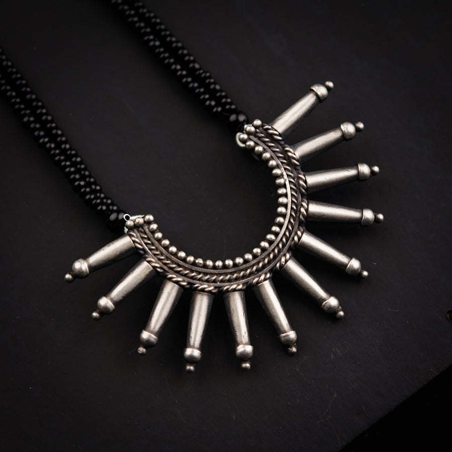 a necklace with silver beads on a black surface