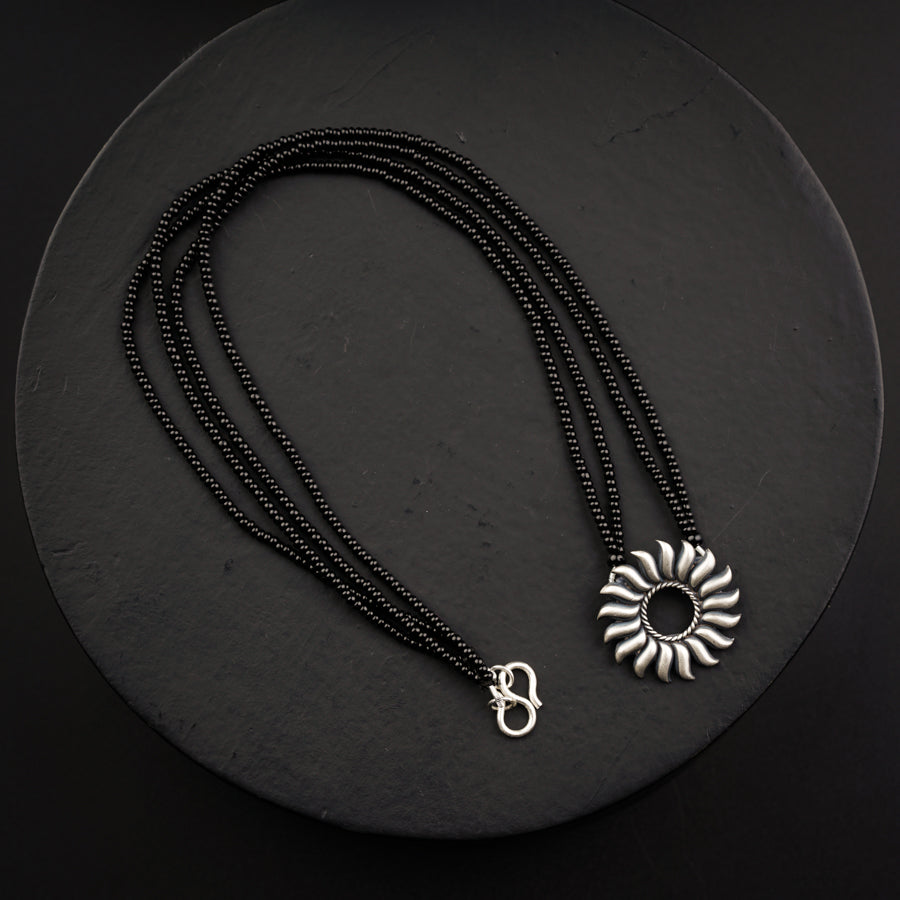 a black beaded necklace with a flower pendant