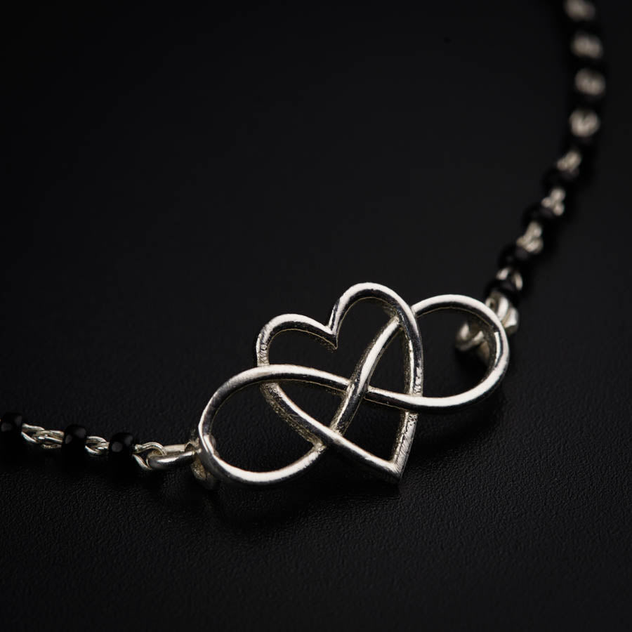 a silver necklace with two intertwined hearts