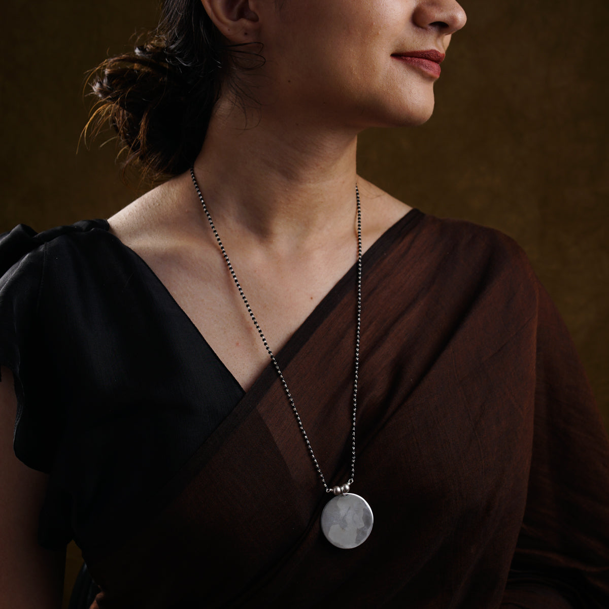 a woman wearing a necklace with a disc on it