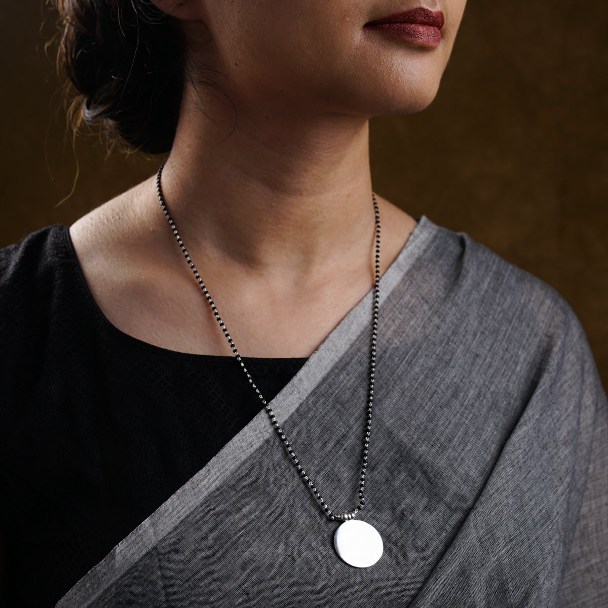a woman wearing a necklace with a disc on it