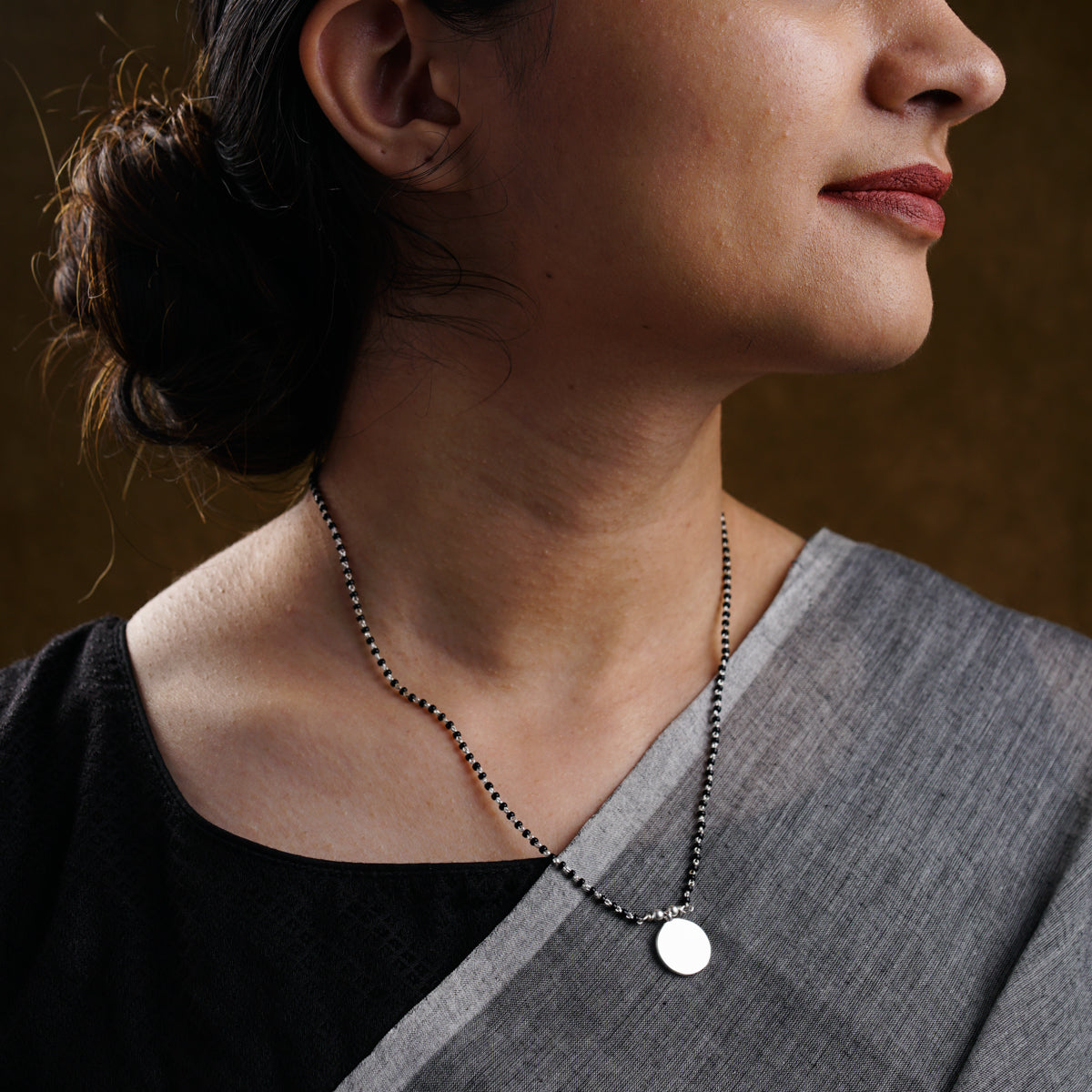 a woman wearing a necklace with a disc on it