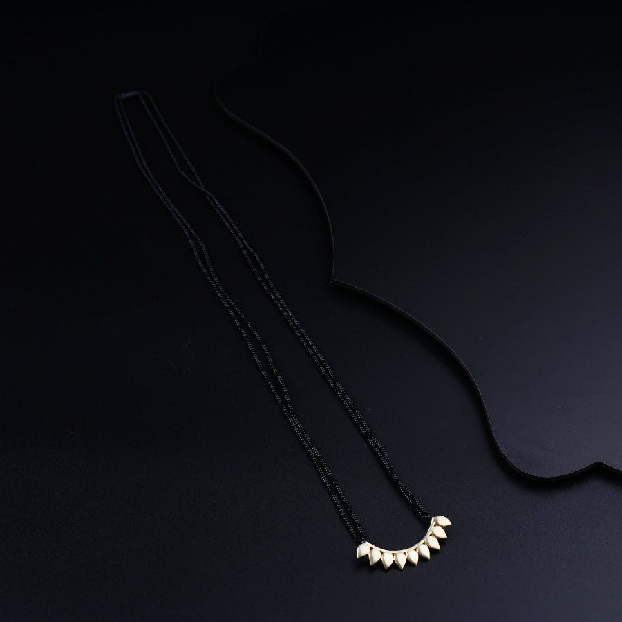 a black necklace with three white beads on a black background