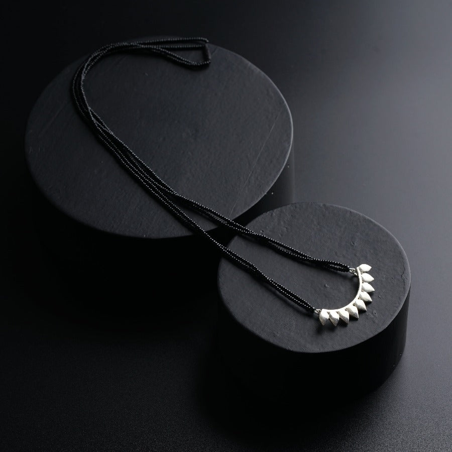 a pair of necklaces sitting on top of a black surface