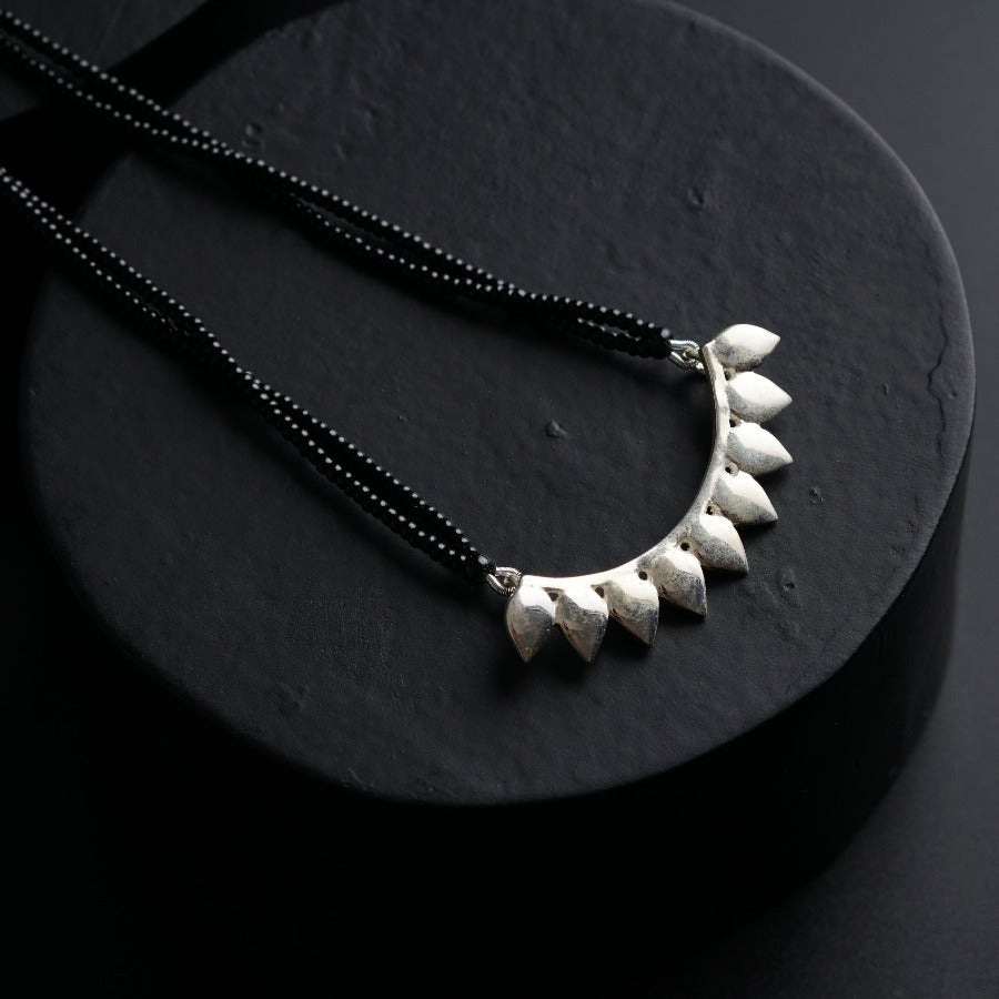 a black necklace with a white flower on it