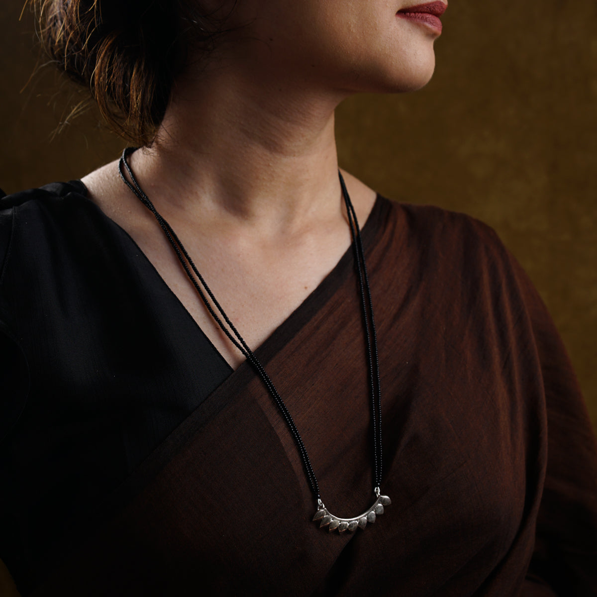 a woman wearing a brown shirt and a necklace