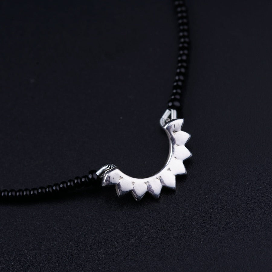 a black beaded necklace with a silver pendant