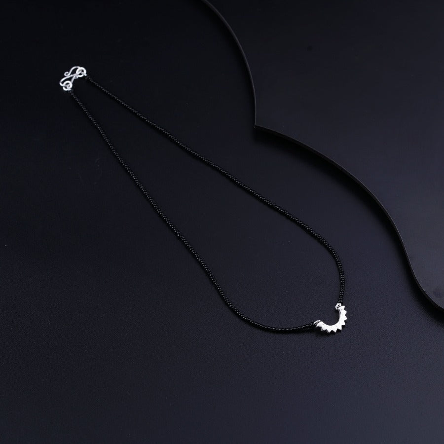 a black necklace with a white moon on it