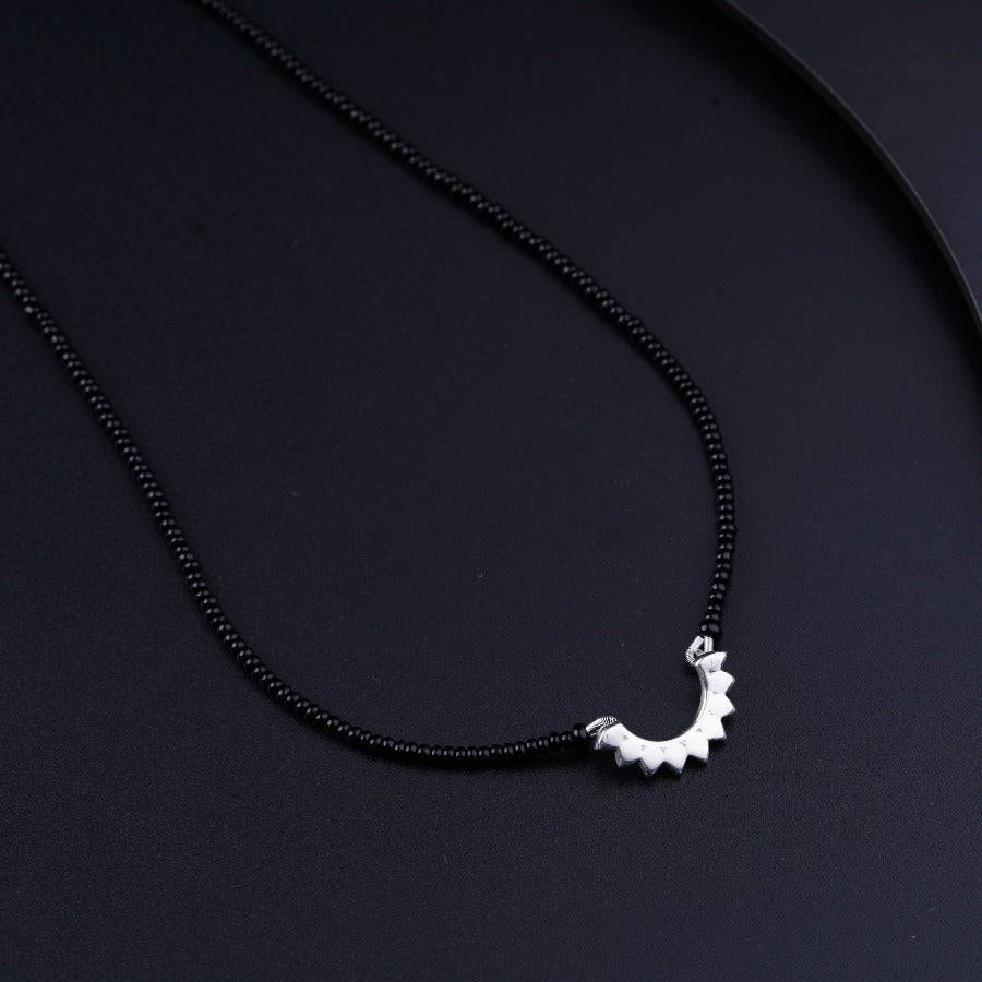 a black necklace with a silver dragon on it