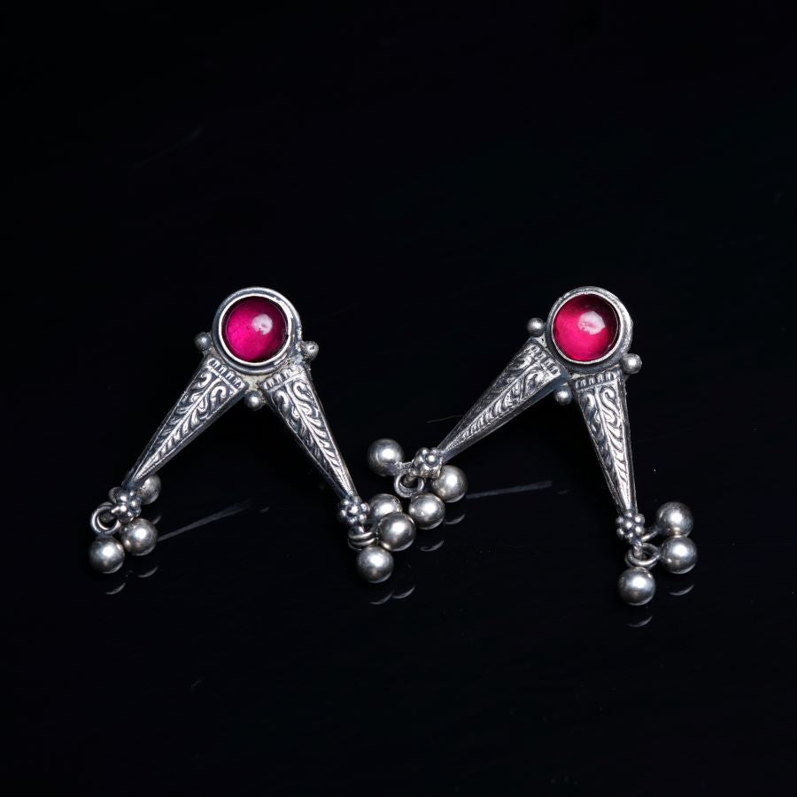 a pair of silver earrings with red stones