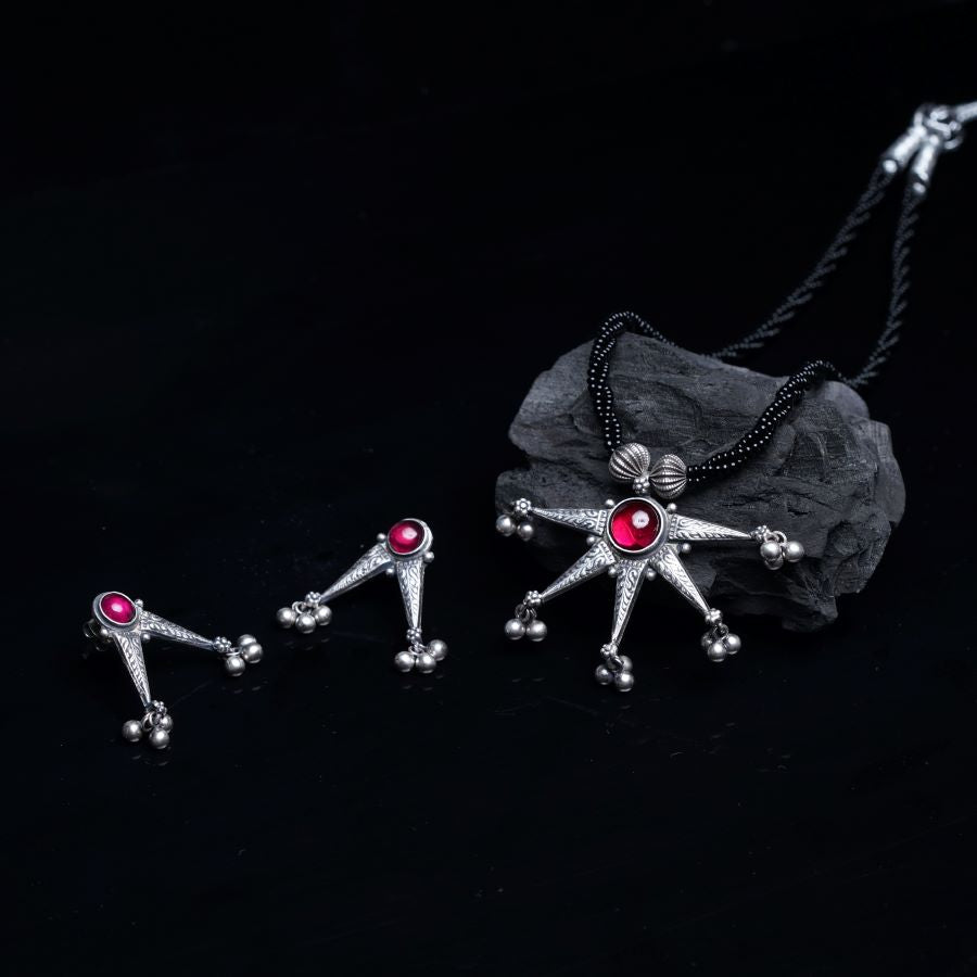 a pair of necklaces with red stones on a black background