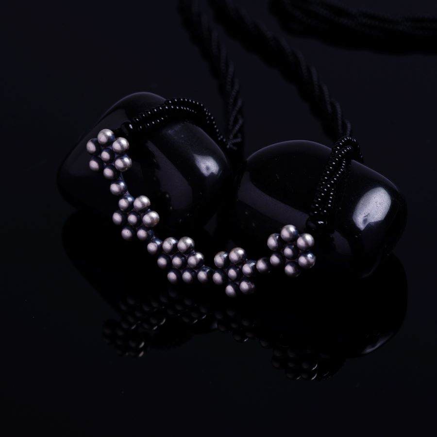a black necklace with pearls on a black background