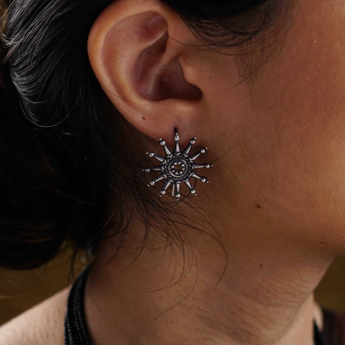 a close up of a person wearing a necklace and earrings