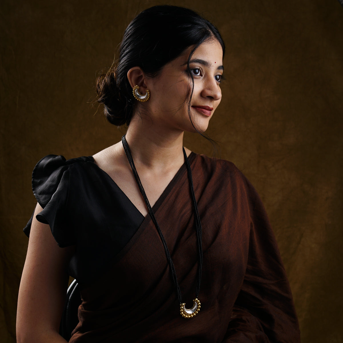 a woman wearing a brown dress and a necklace