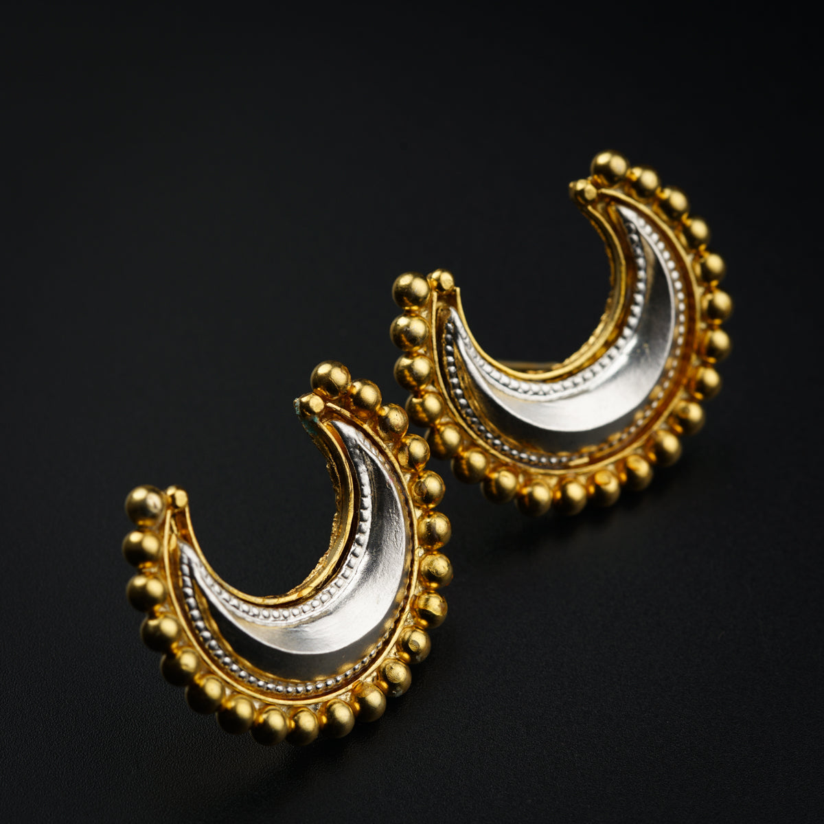 a pair of gold and silver earrings on a black background