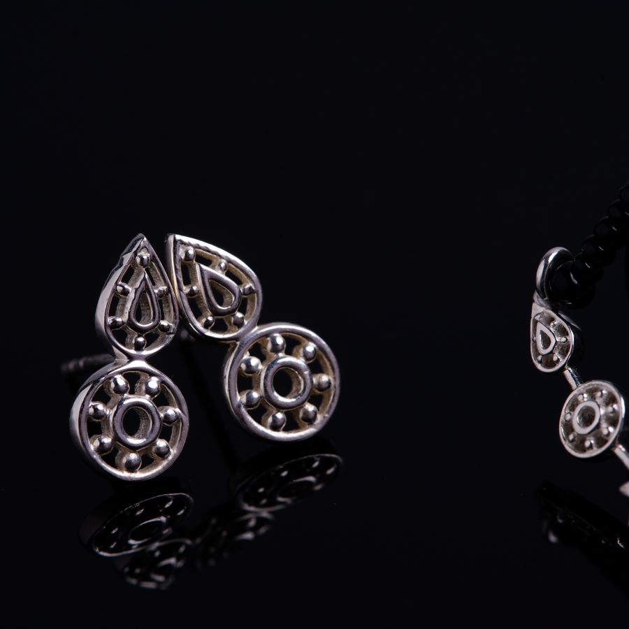 a pair of earrings sitting on top of a black surface
