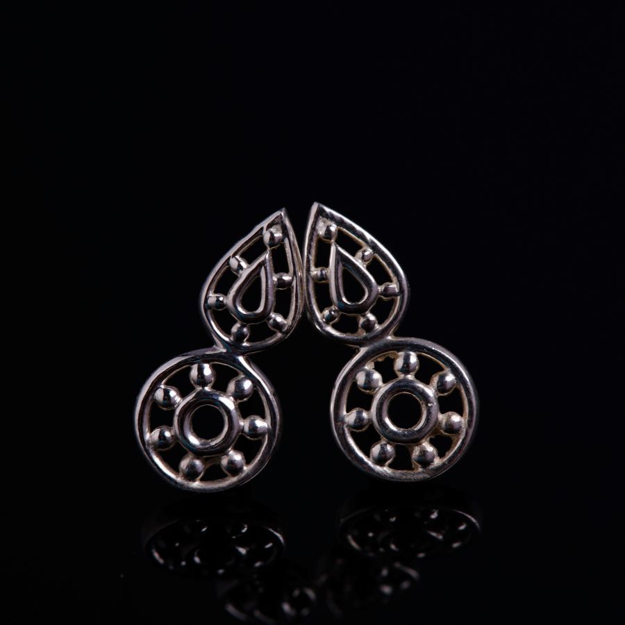 a pair of earrings sitting on top of a black surface