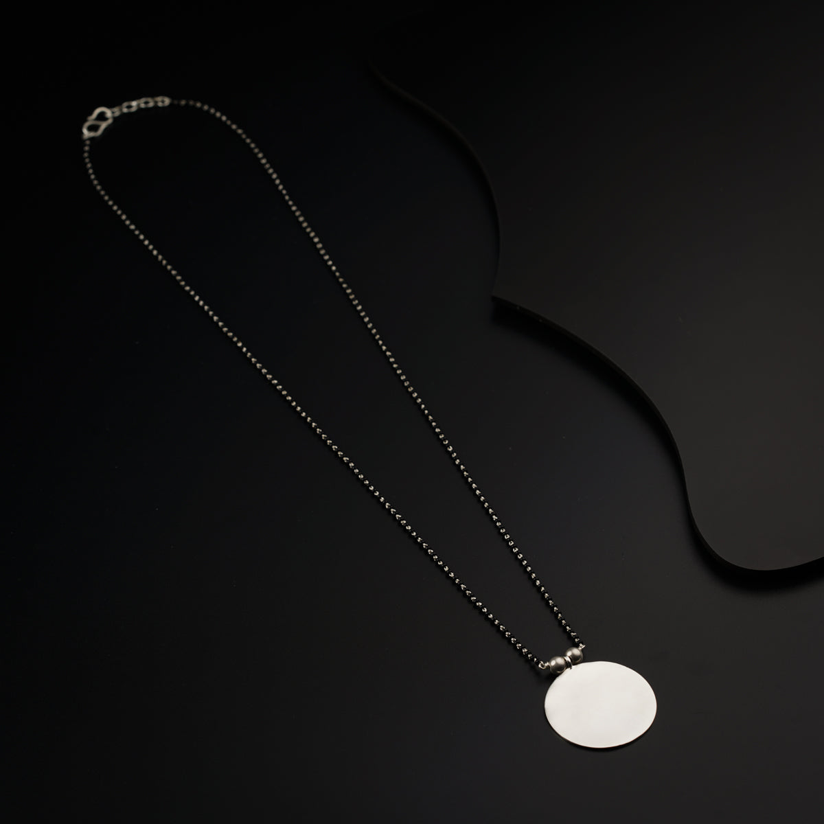 a necklace with a white disc on a black background