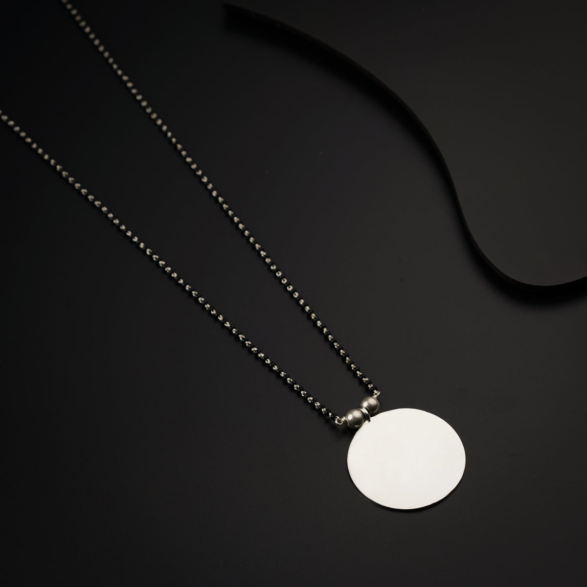 a necklace with a white disc on a black background