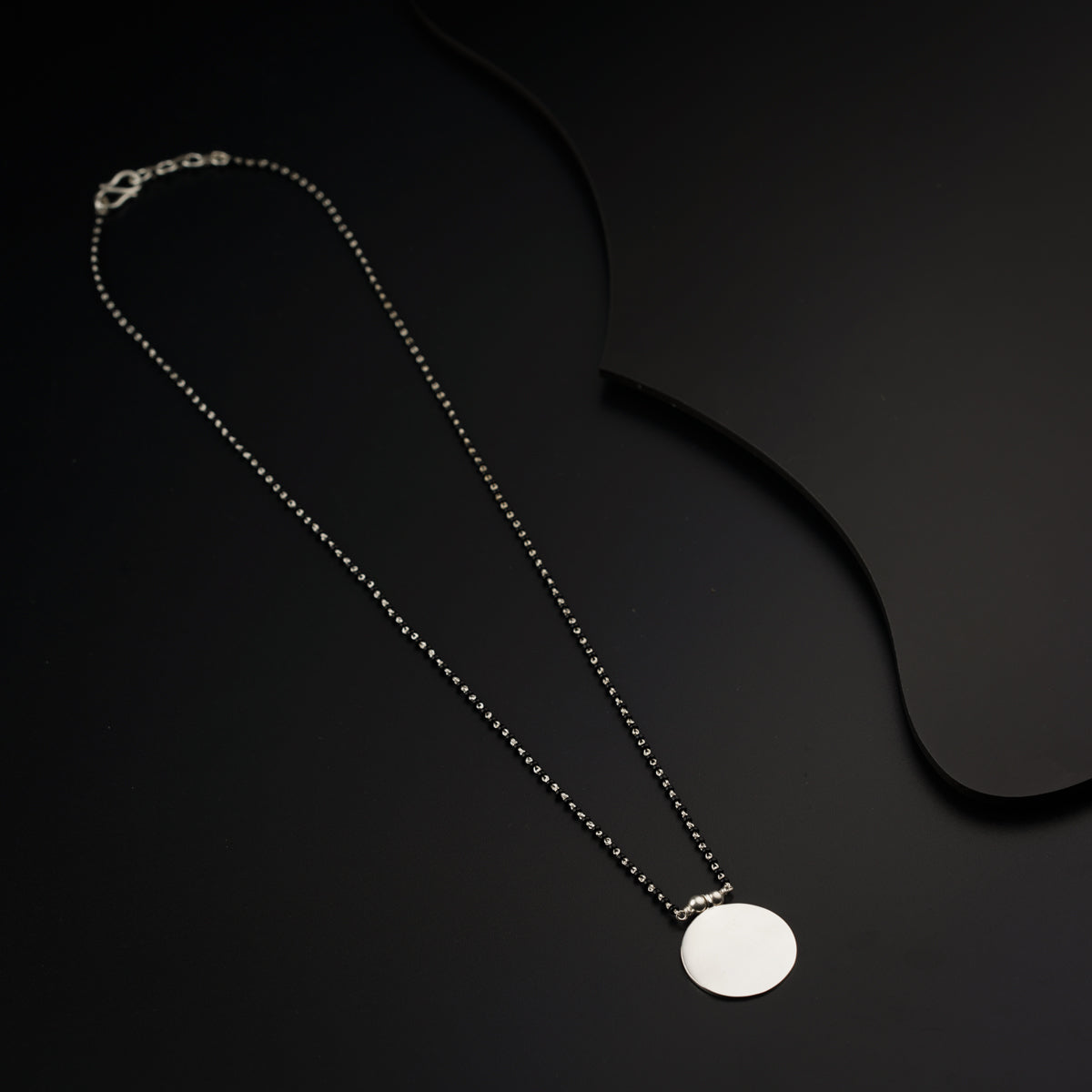 a necklace with a white disc on a black background