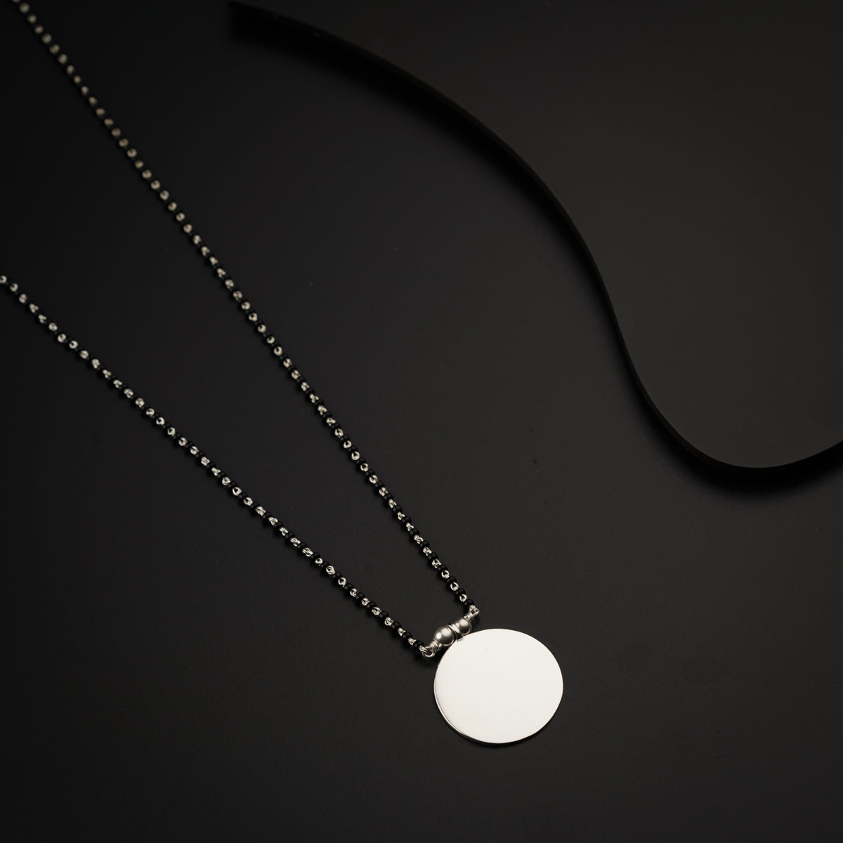 a necklace with a disc on a black background