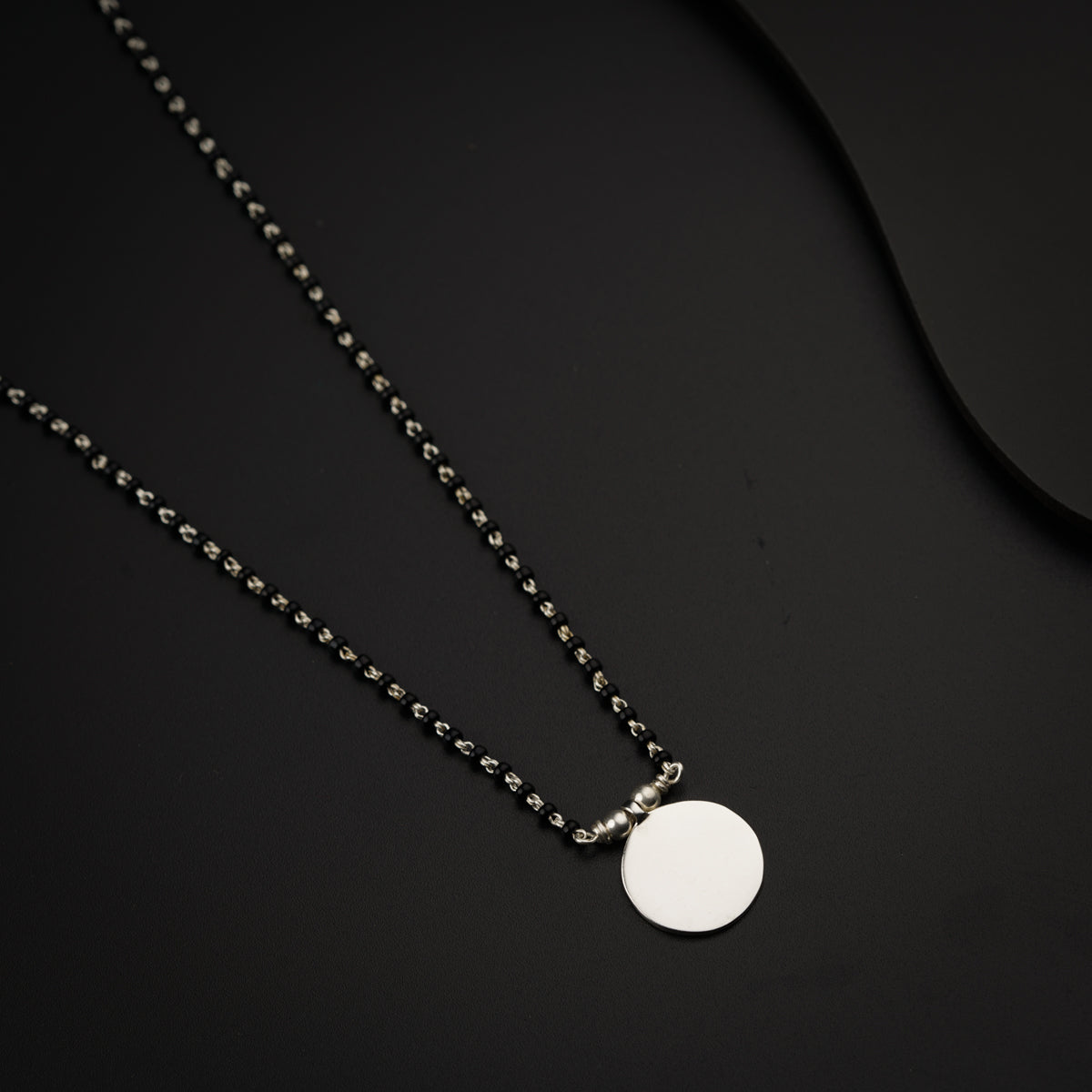 a necklace with a white disc on a black background