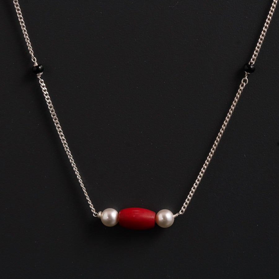 a red and white necklace on a black surface