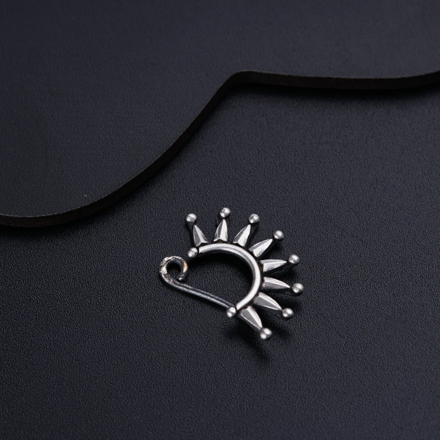 a silver brooch with spikes on a black background