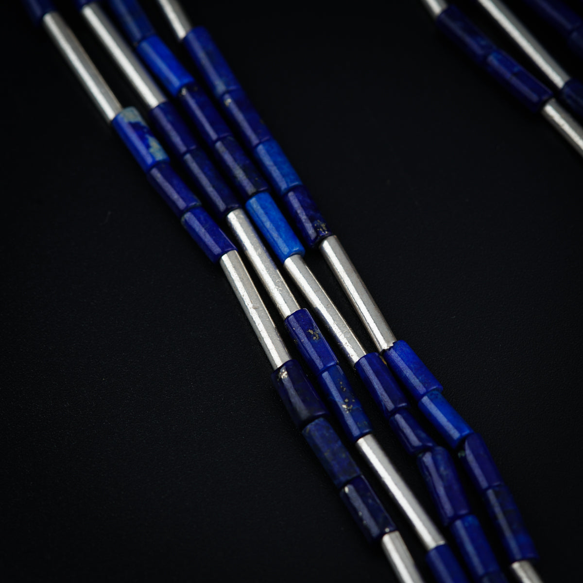 a group of blue and silver beads on a black surface