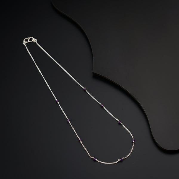 a silver necklace with a purple bead on a black background