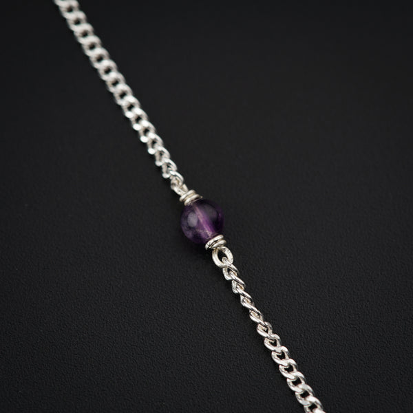 a silver chain with a purple bead on it