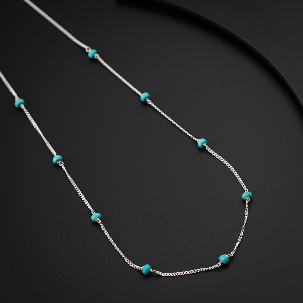a necklace with turquoise beads on a black surface