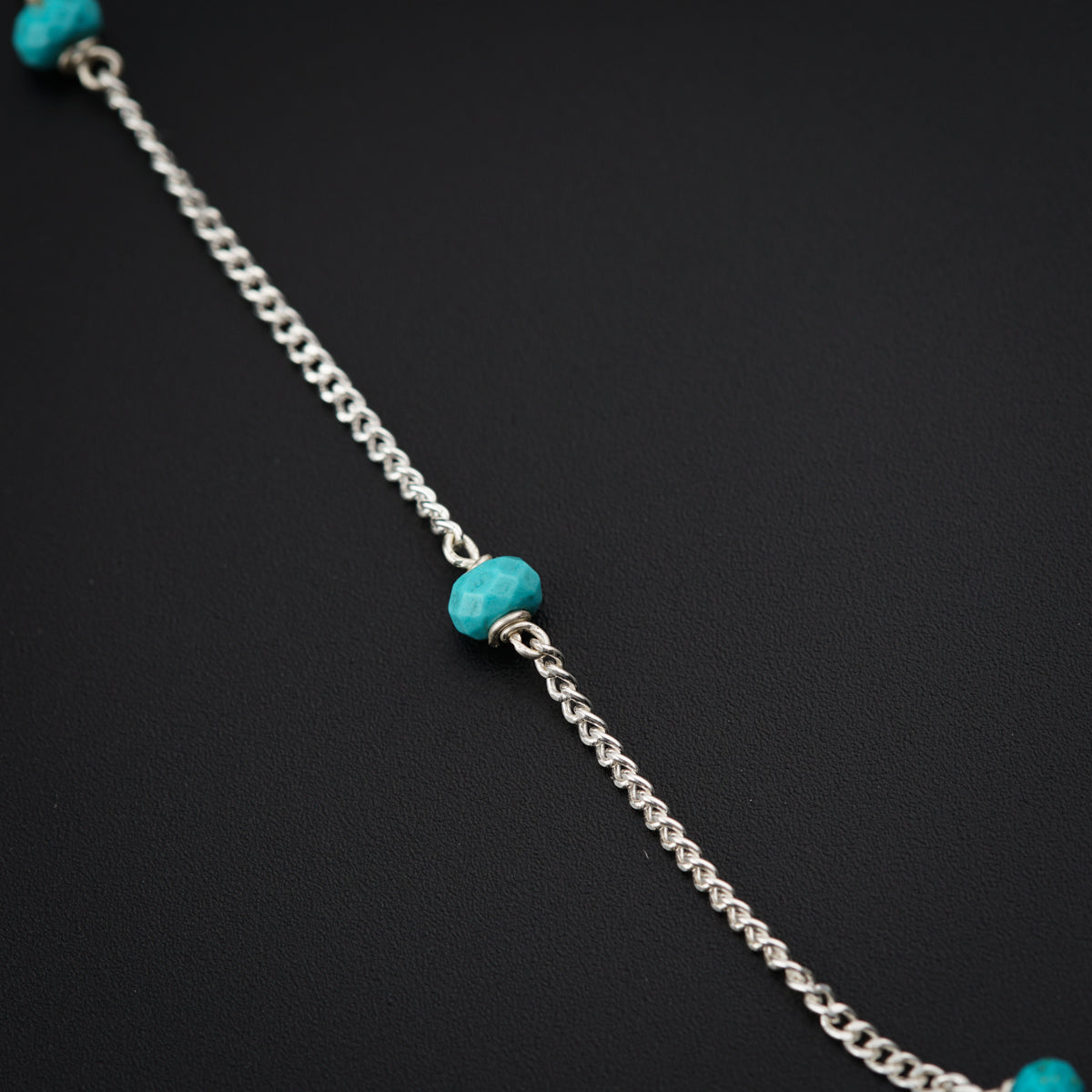 a silver chain with a turquoise bead on it