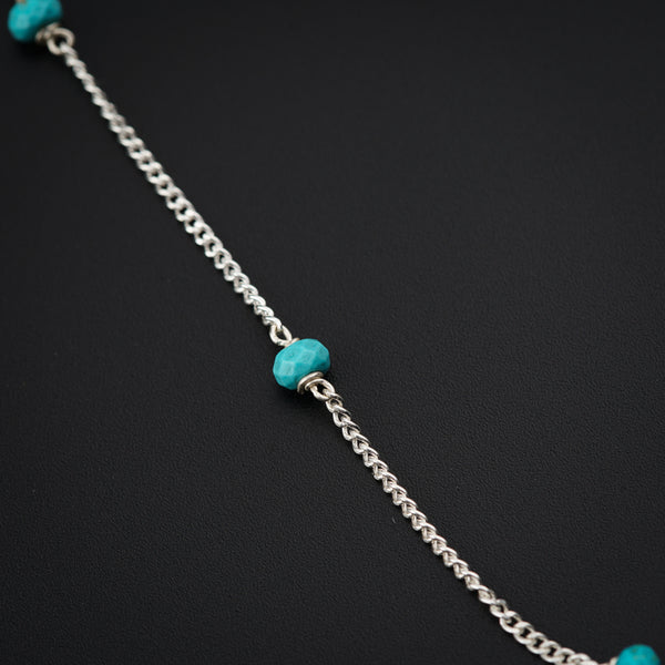a silver chain with a turquoise bead on it