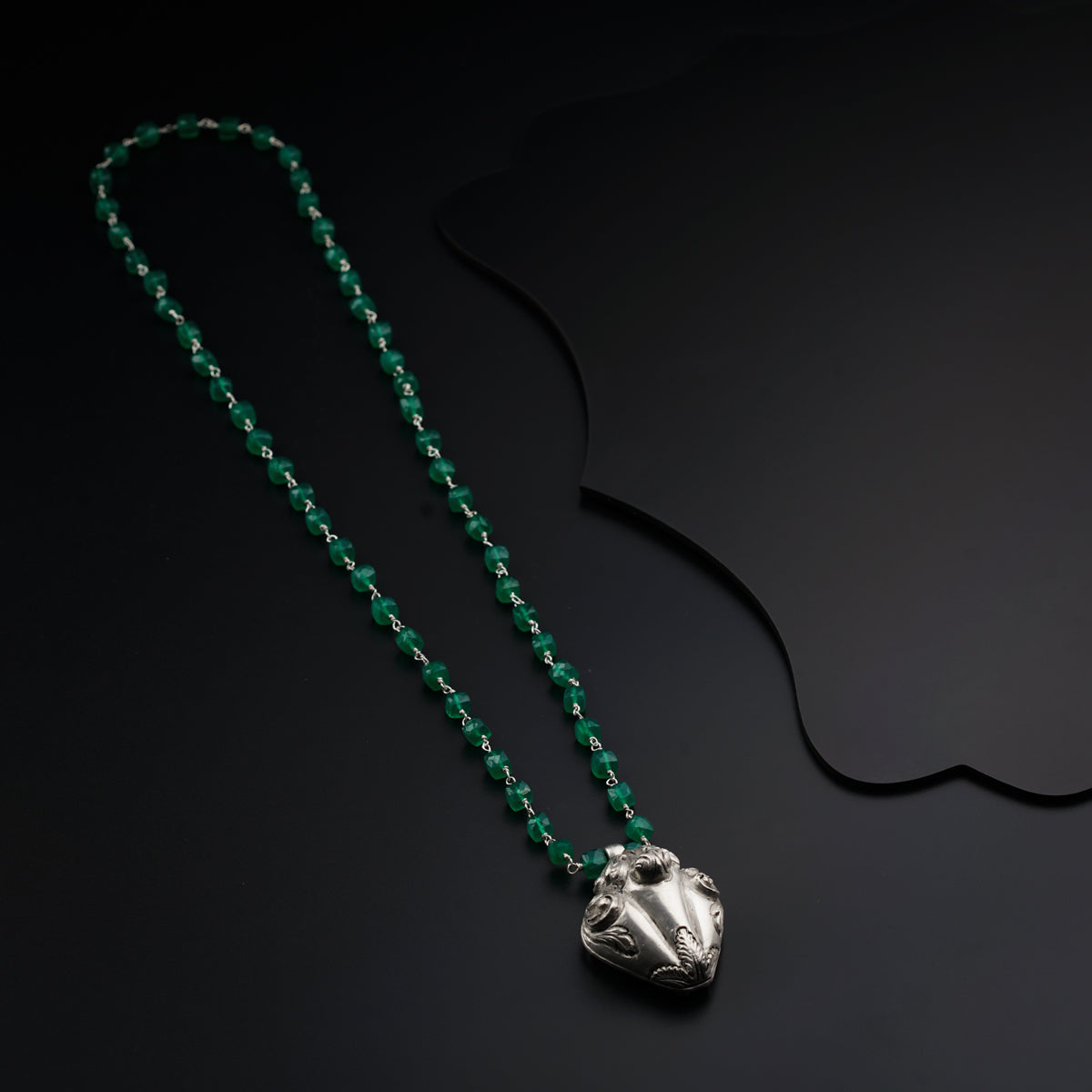 a green beaded necklace with a silver pendant