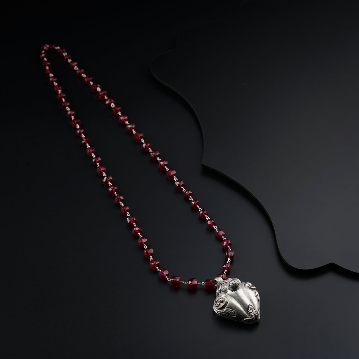 a red beaded necklace on a black surface