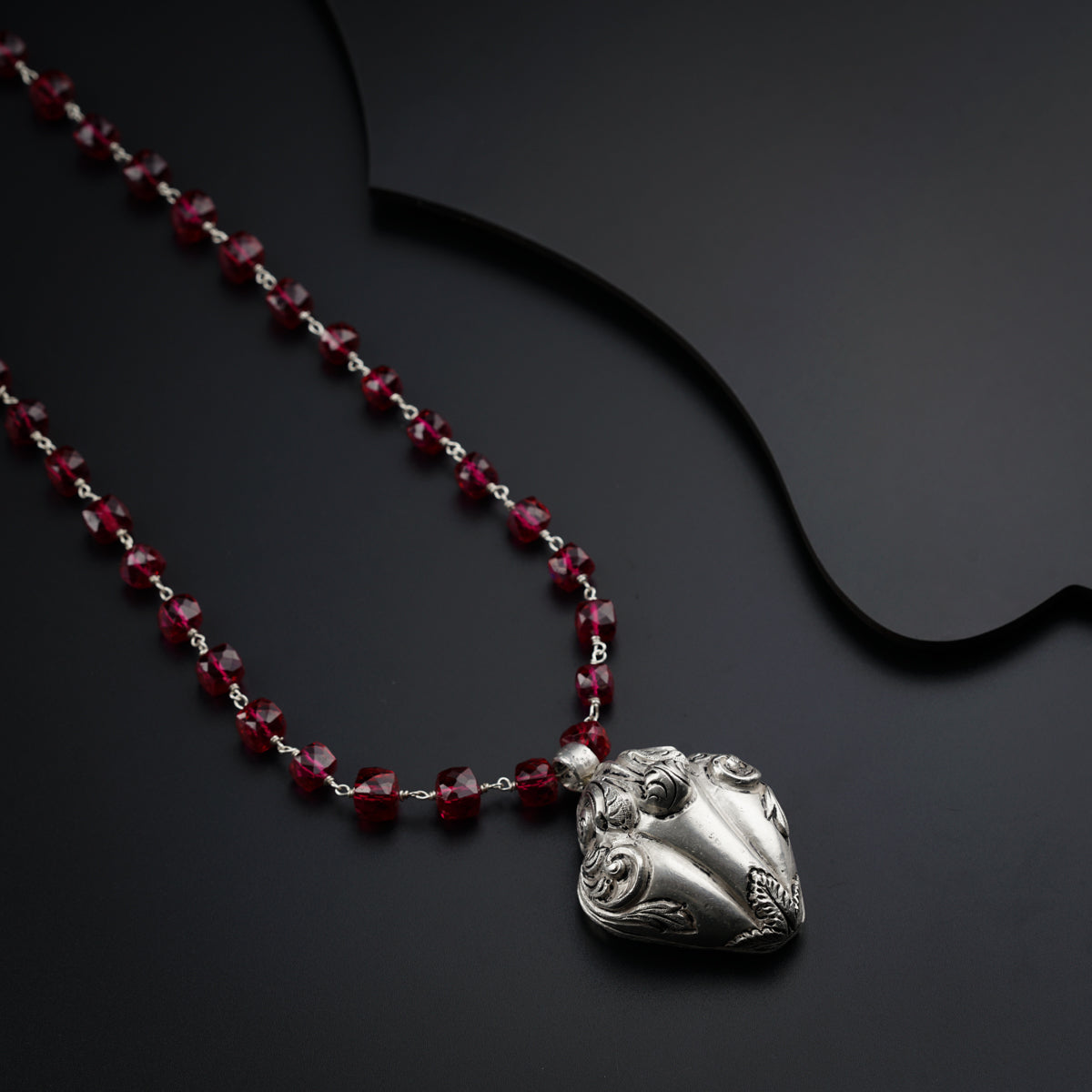 a red beaded necklace with a silver heart on it